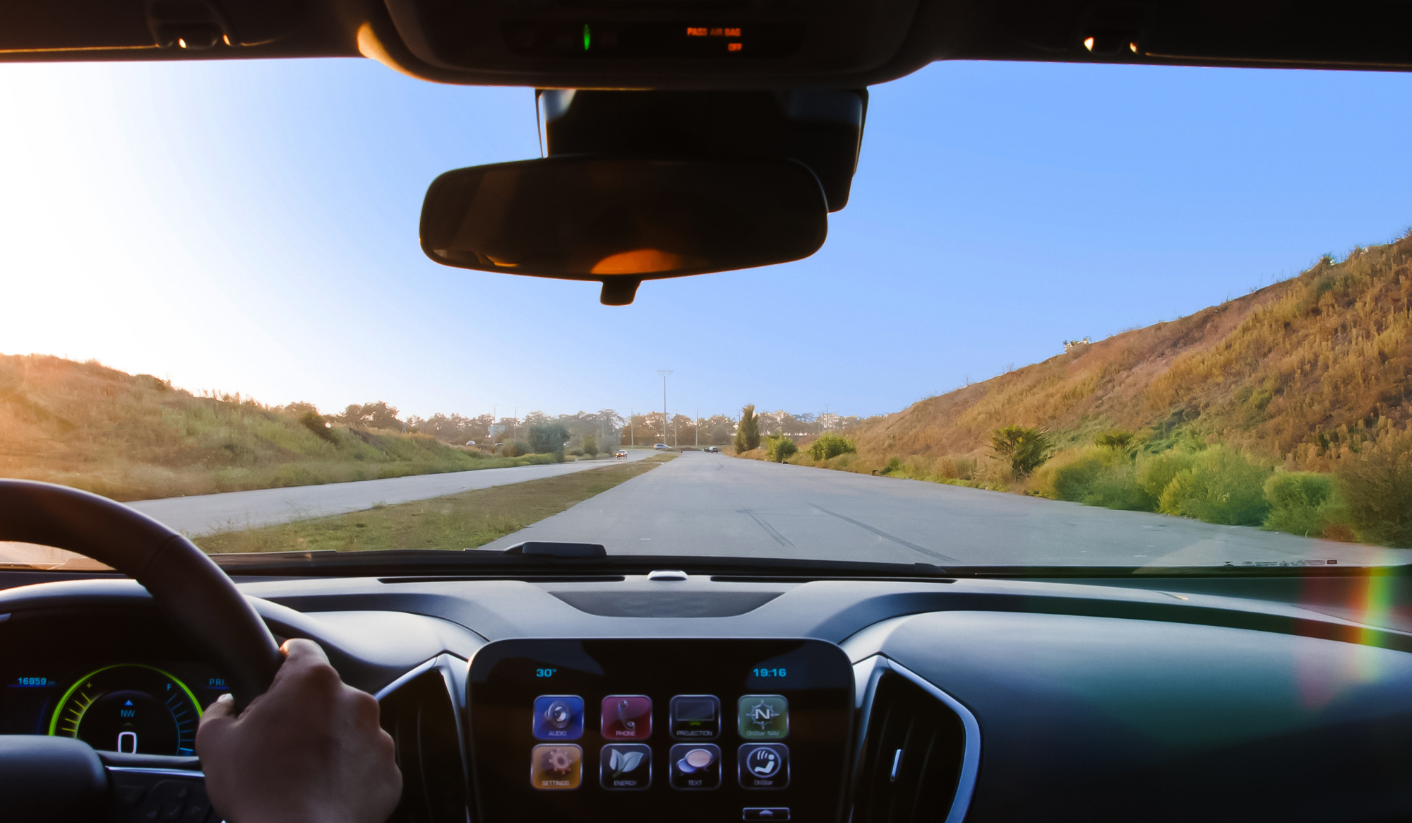 View from inside a vehicle showcasing a clear windshield, dashboard display, and an open road lined with greenery, emphasizing the importance of windshield care and maintenance for Florida drivers.